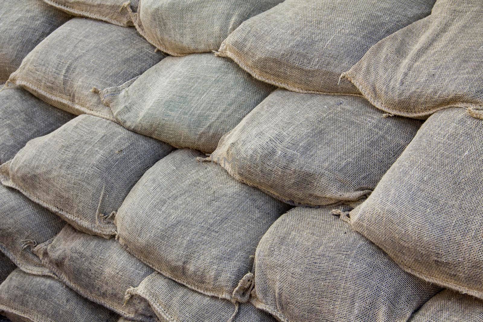 Background of lying dirty sandbags. Sandbag flood protection wall texture, texture. Bags to strengthen the defensive structure during the battle. Background