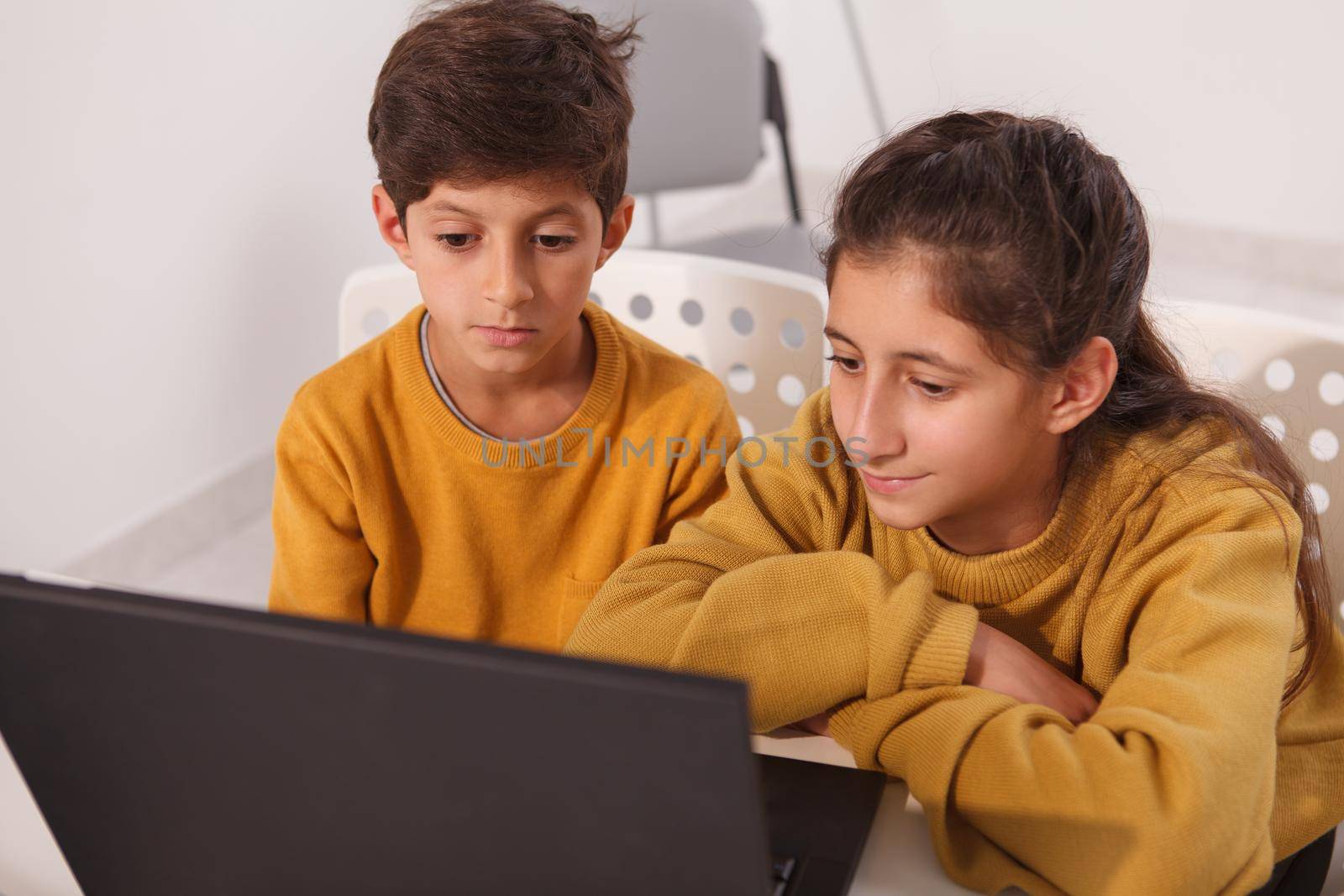 Top view shot of two lovely Arabic kids, brother and sister studying online