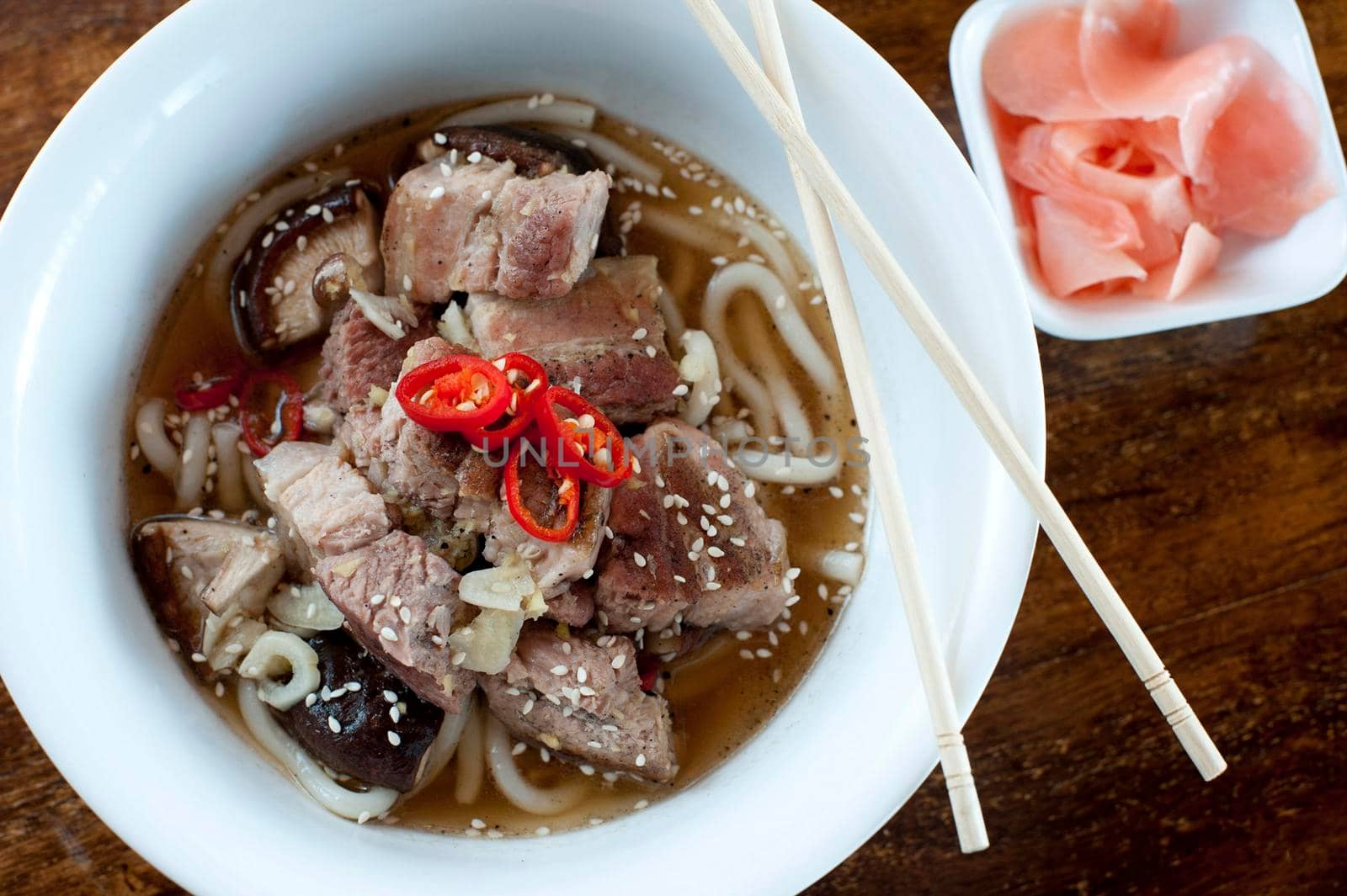 Bowl of ramen, a traditional Japenese meal of noodles in a broth, garnished with pork chunks, overhead view in a bowl