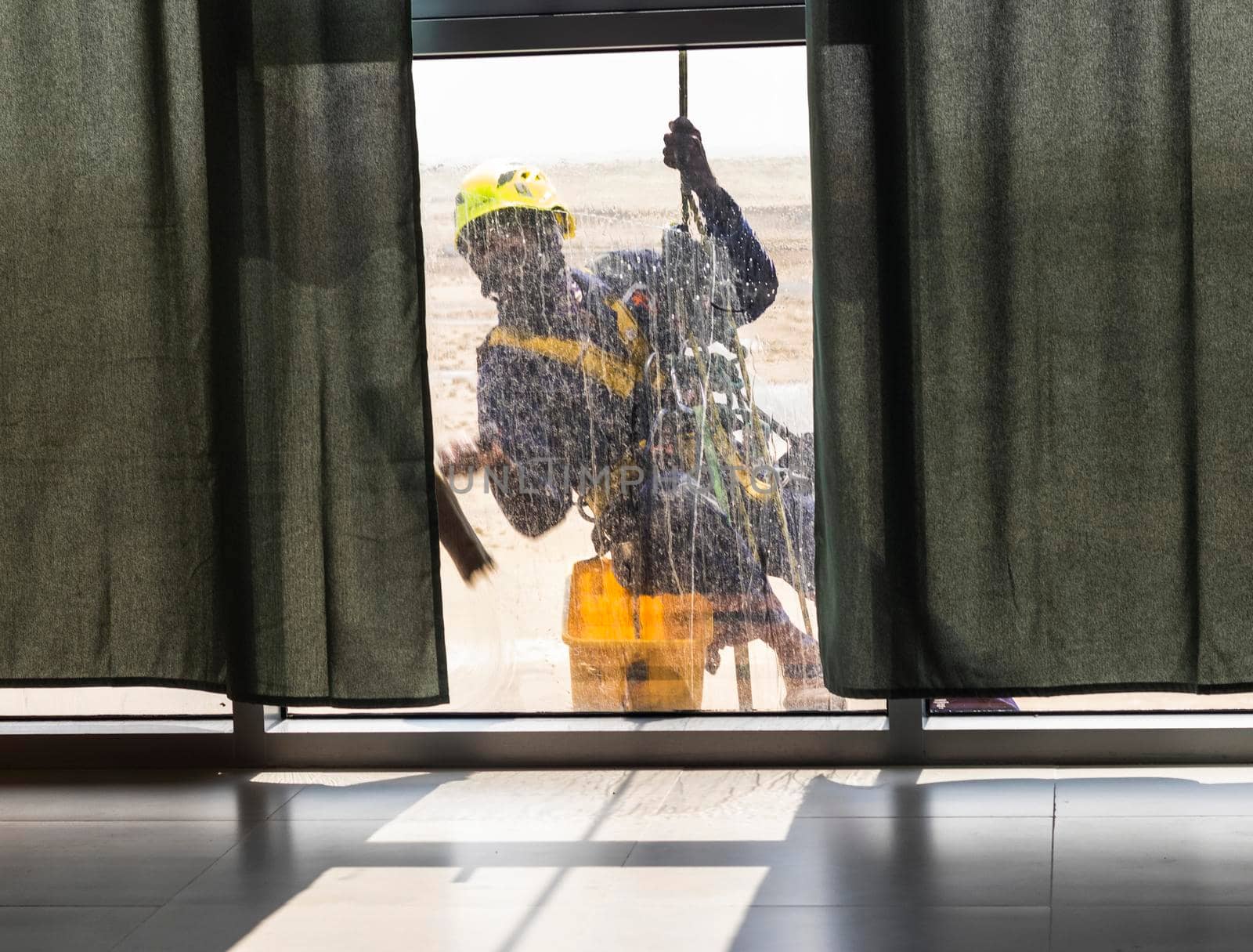 Silhouette of a rope access glass cleaner working at heights.