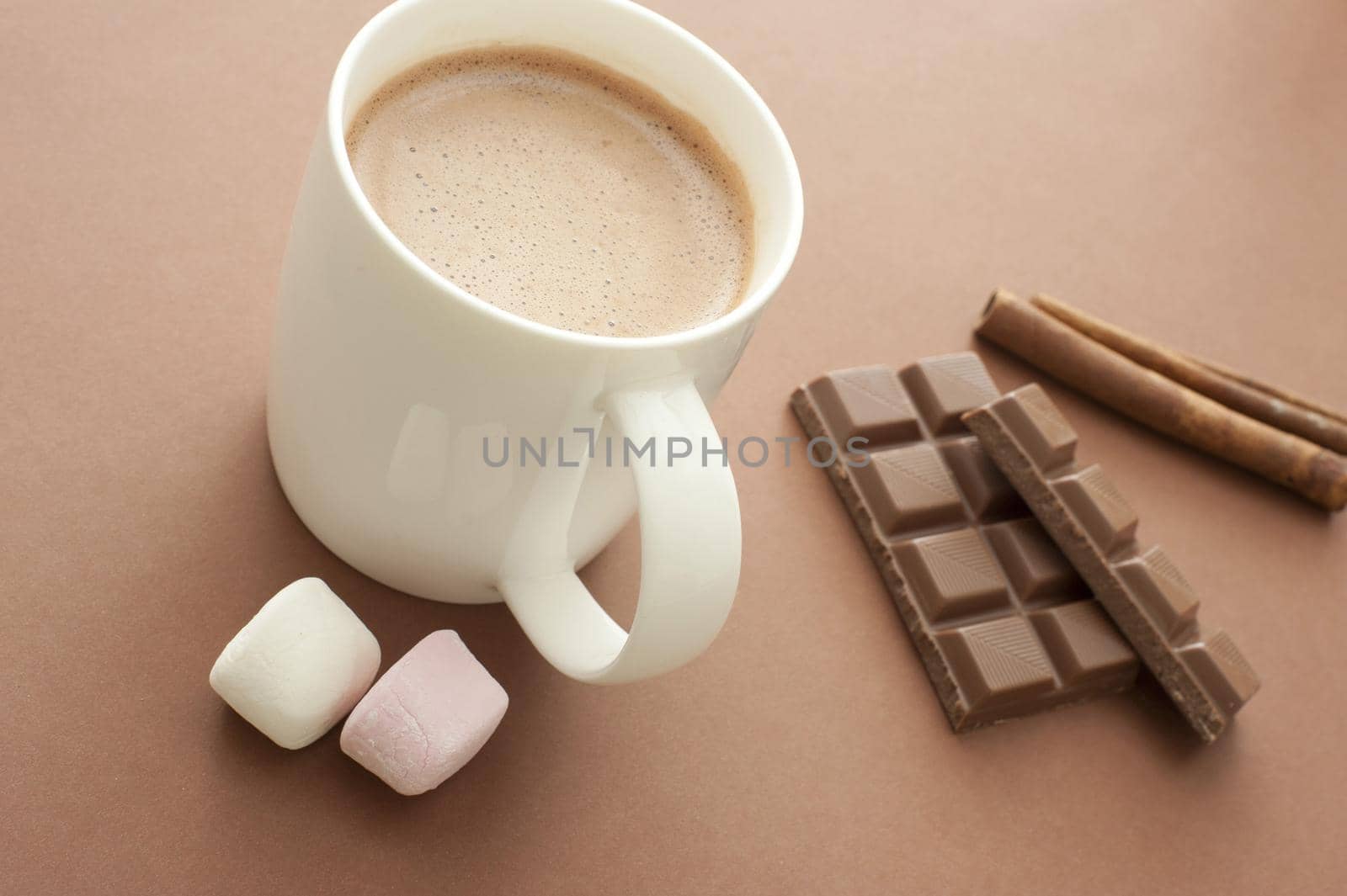 Hot chocolate drink with ingredients including marshmallows, stick cinnamon and a candy chocolate bar for a delicious winter beverage, high angle view