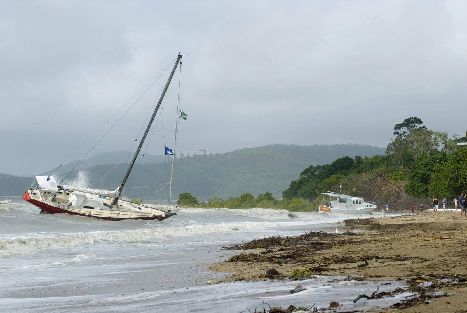 Shipwrecked yacht lies aground near the shore during storm wind in tropical sea