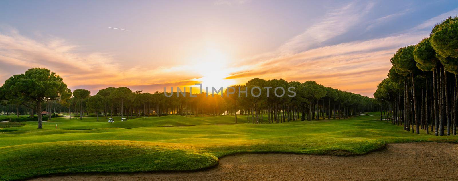 Golf course at sunset with beautiful sky. Scenic panoramic view of golf fairway