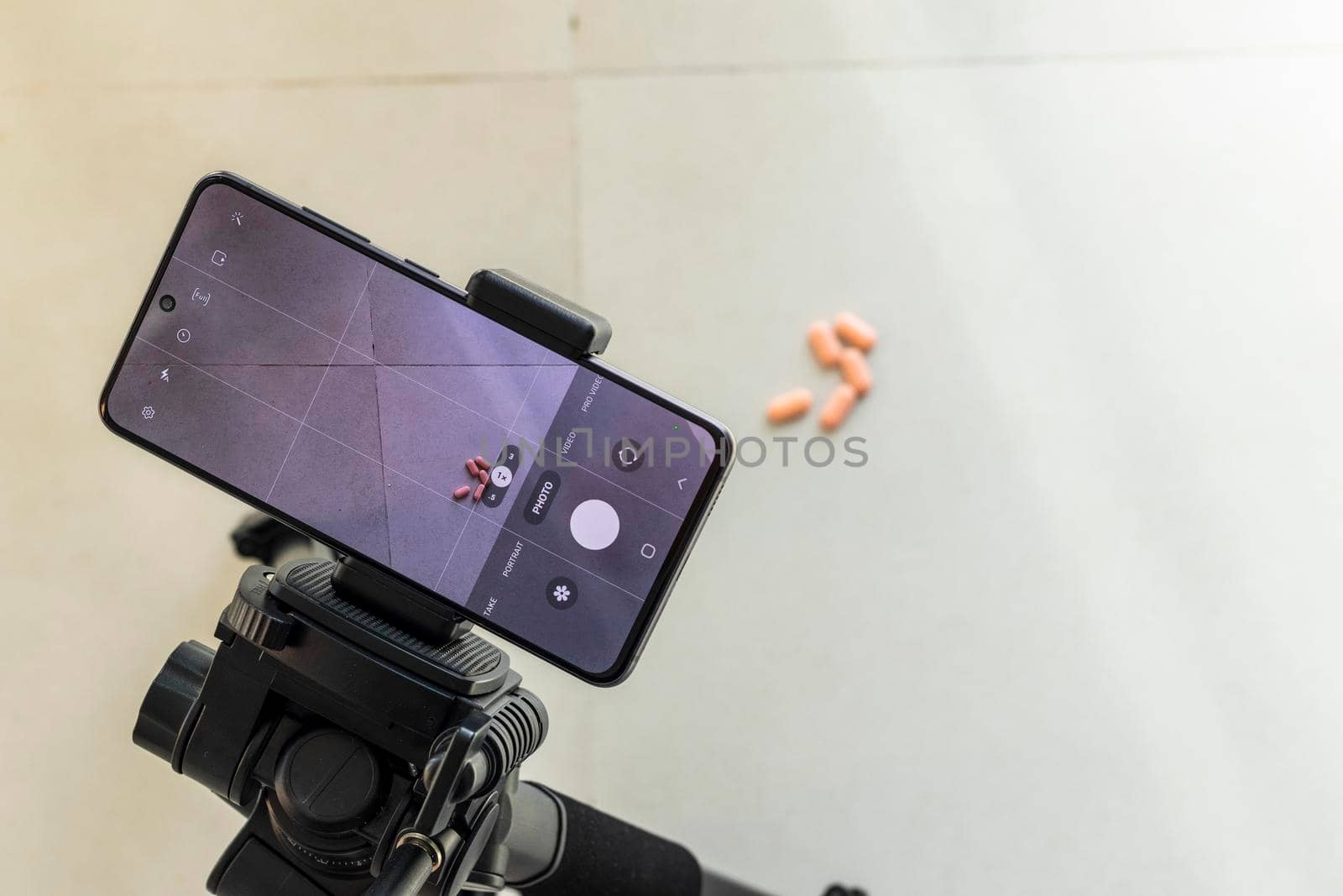 Close up shot of a phone on tripod capturing medicine on the surface