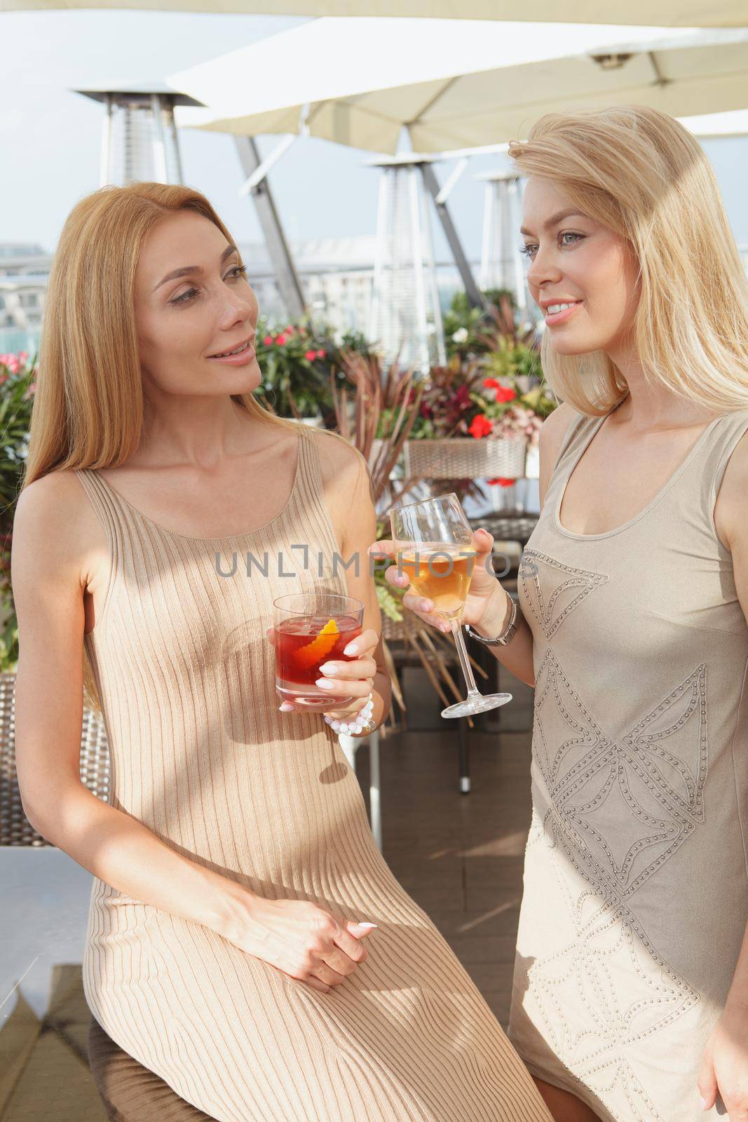 Vertical shot of two beautiful woman talking over drinks at outdoor restaurant