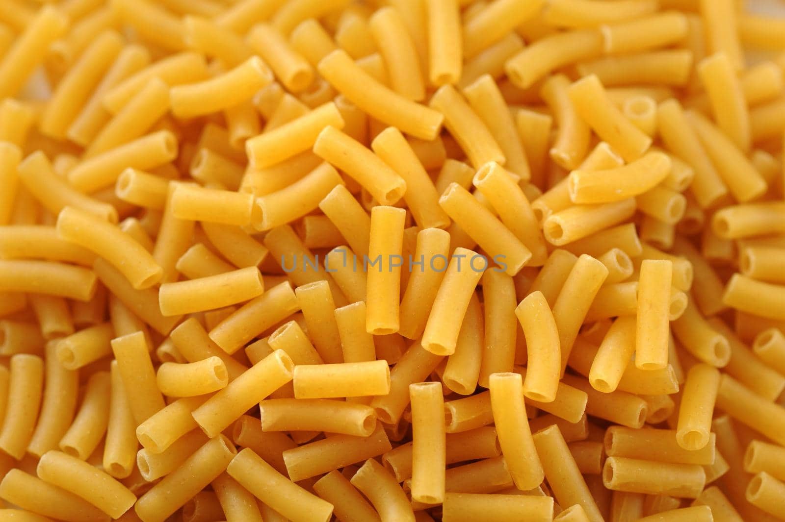 Macaroni background texture with a heap of dried pasta tubes in a full frame view for Italian and Mediterranean cuisine