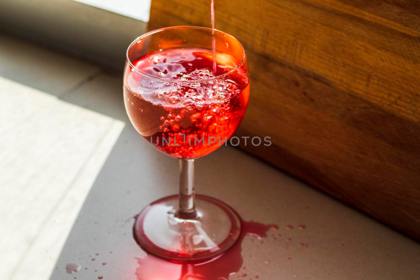 Shot of a red liquid being poured in to the wine glass.