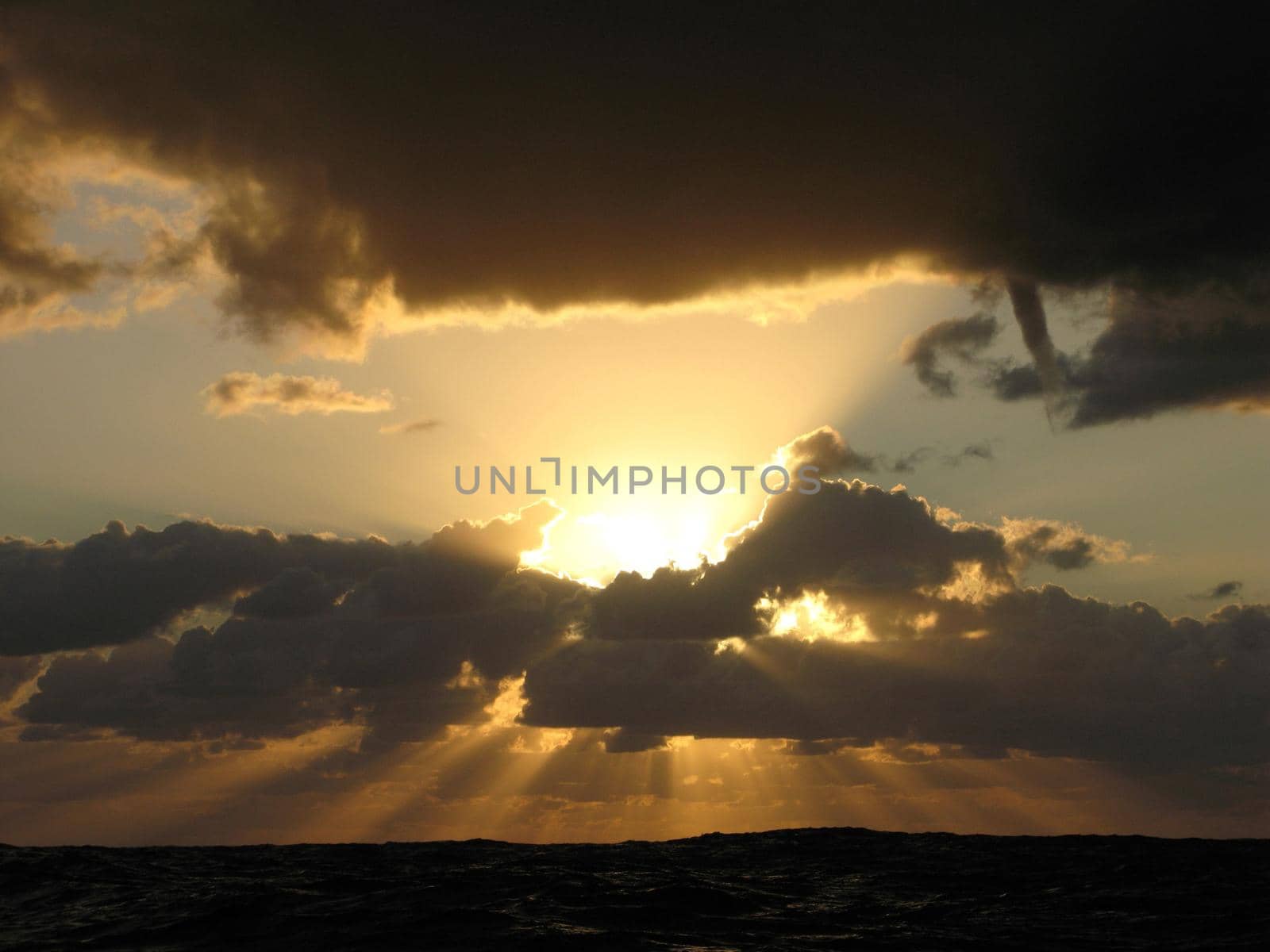 sunbeams breaking through a cloud in a stormy ocean