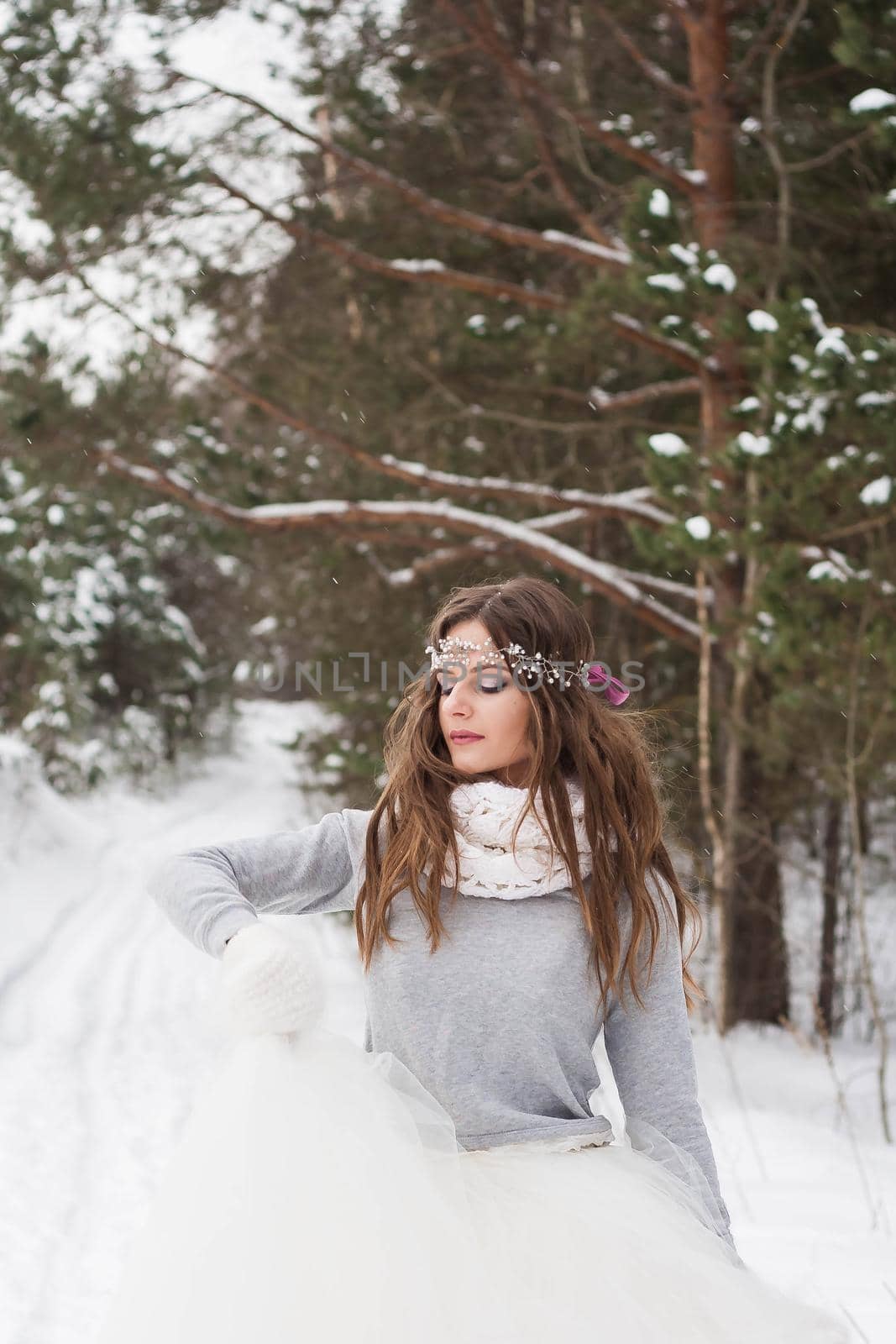 Beautiful bride in a white dress with a bouquet in a snow-covered winter forest. Portrait of the bride in nature.