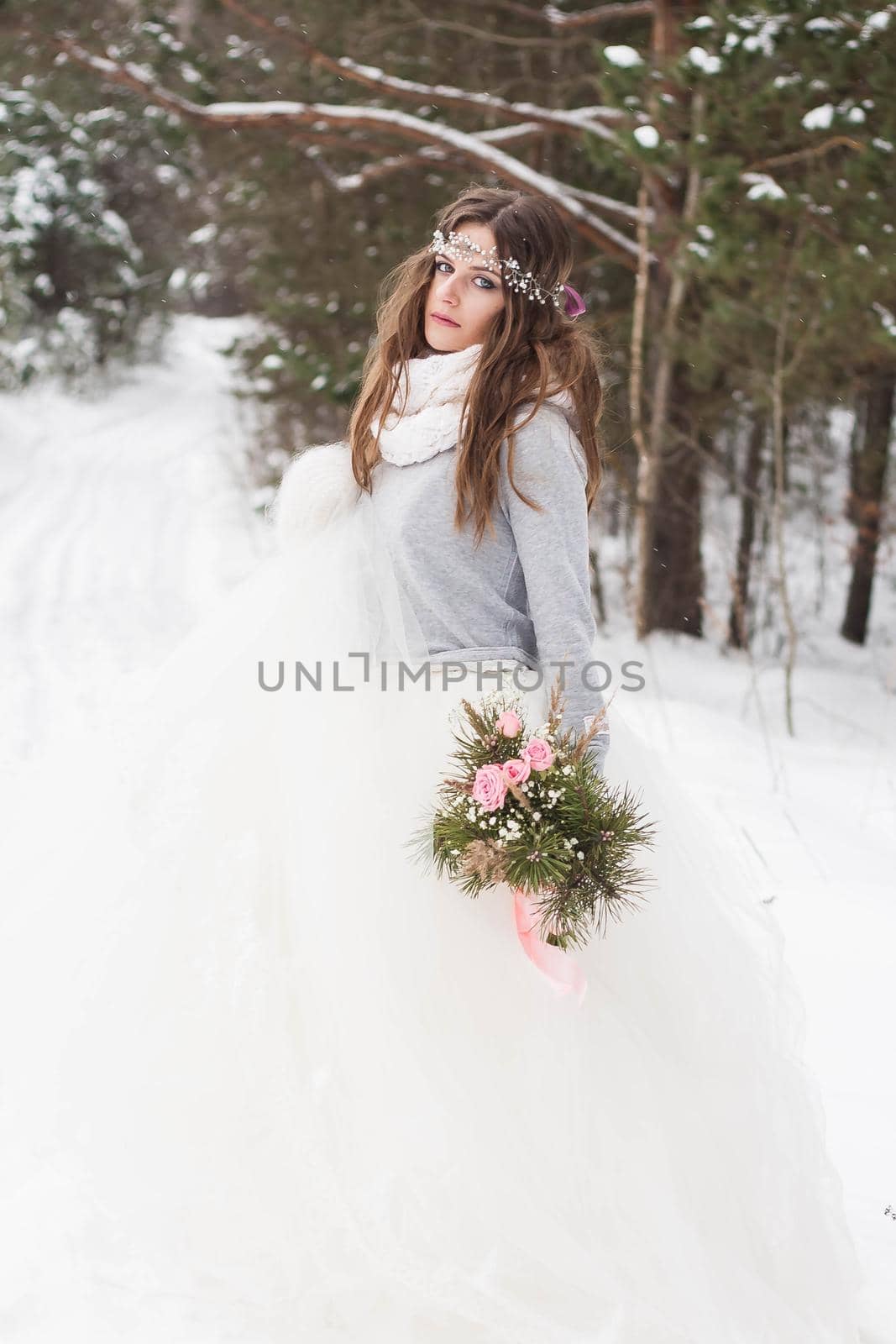 Beautiful bride in a white dress with a bouquet in a snow-covered winter forest. Portrait of the bride in nature by Annu1tochka