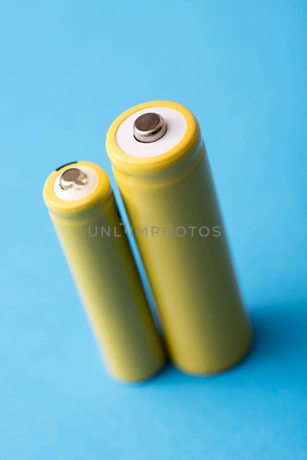 Two yellow baterries in different sizes standing on blue background