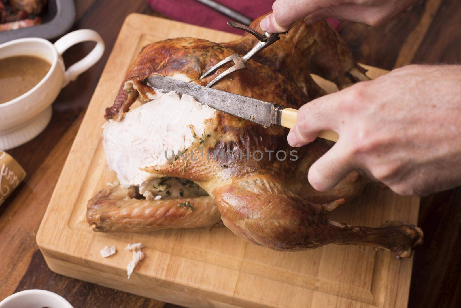a man slicing meat from a christmas festive dinner roast turkey