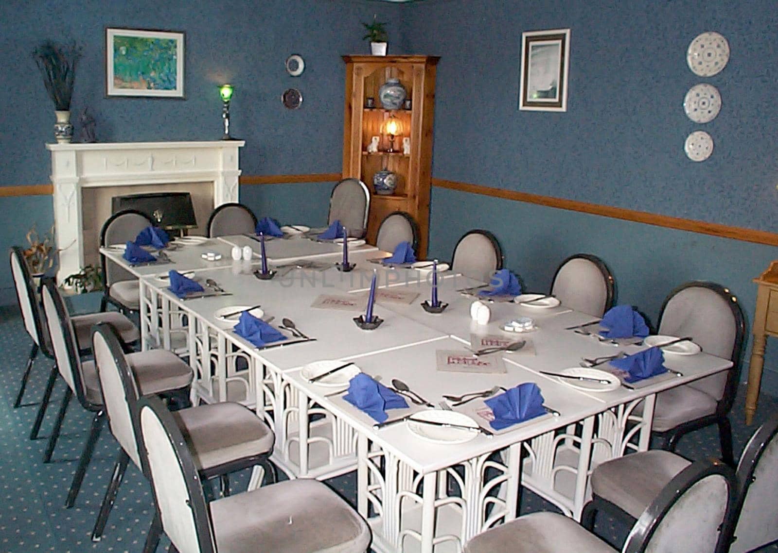 Stylish modern white dining suite with a long table and chairs set with twelve formal place settings in blue decor