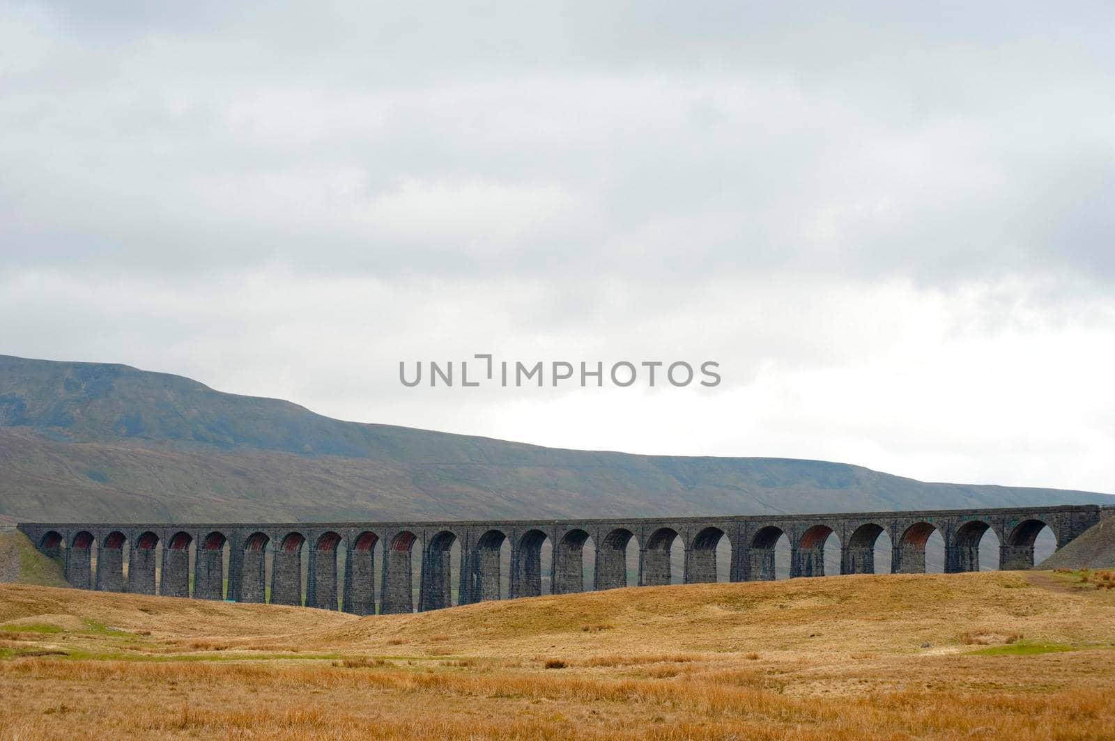 Panoramic view of the stone arches of the Ribblehead Viaduct, a curved stone Victorian railway viaduct crossing the River Ribble in North Yorkshire