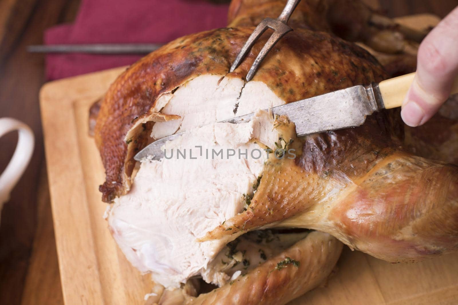 Man carving a roast turkey slicing the breast with old fashioned bone handled utensils in a close up view