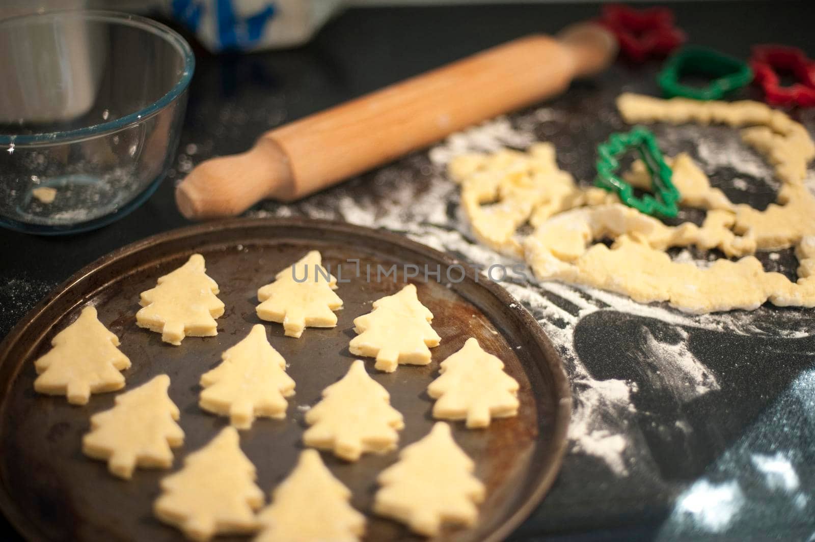 Baking homemade Christmas cookies with pastry cut out in the shape of traditional Christmas trees arranged on a baking tray to go into the oven