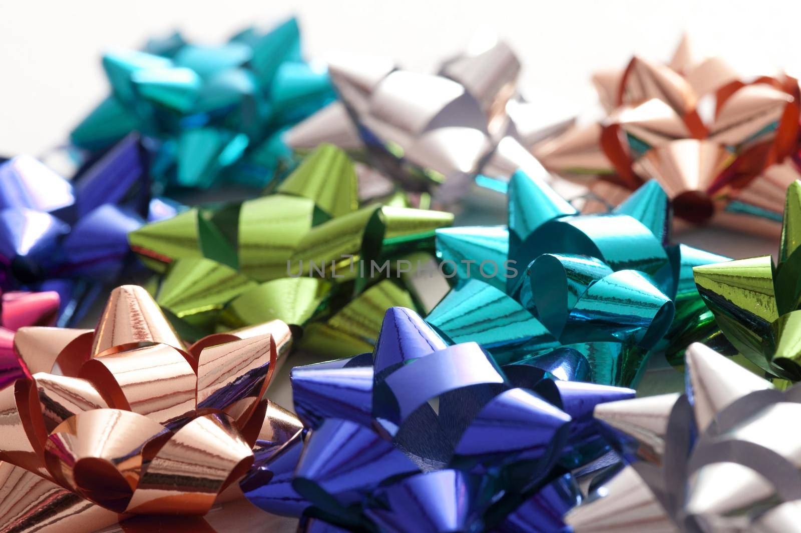Full Frame Background of Colorful Metallic Gift Bows Scattered on White Background with Copy Space