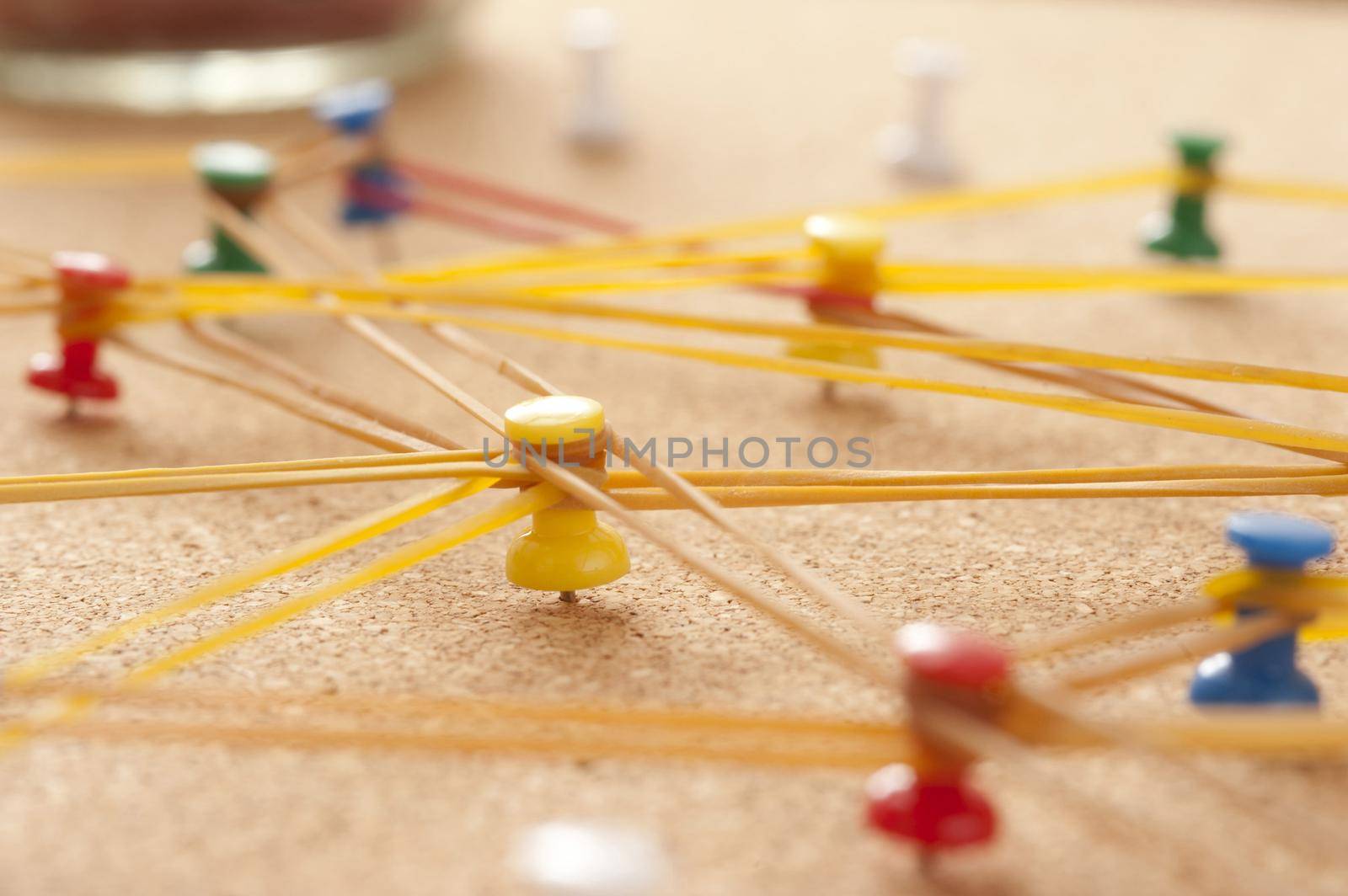 Team Concept - Close up Colored Pins on Cork Board Connected with Rubber bands