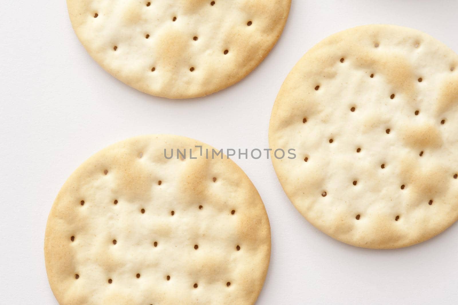 Water crackers background with an overhead view of plain crispy water biscuits made from flour and water served to accompany a cheese platter, on white