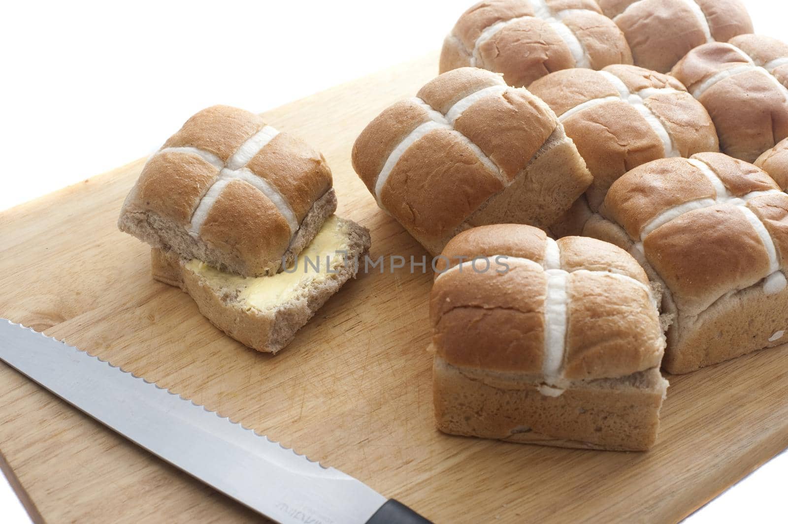 Buttered Fresh Hot Cross Buns on a wooden board to celebrate Easter