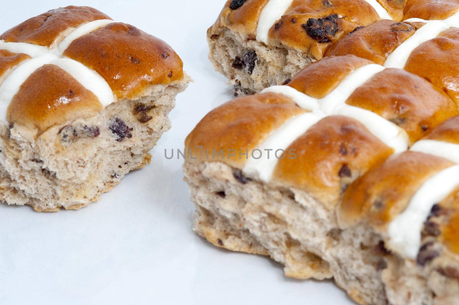 Freshly baked spicy Easter hot cross buns with glazed white pastry crosses on a white background