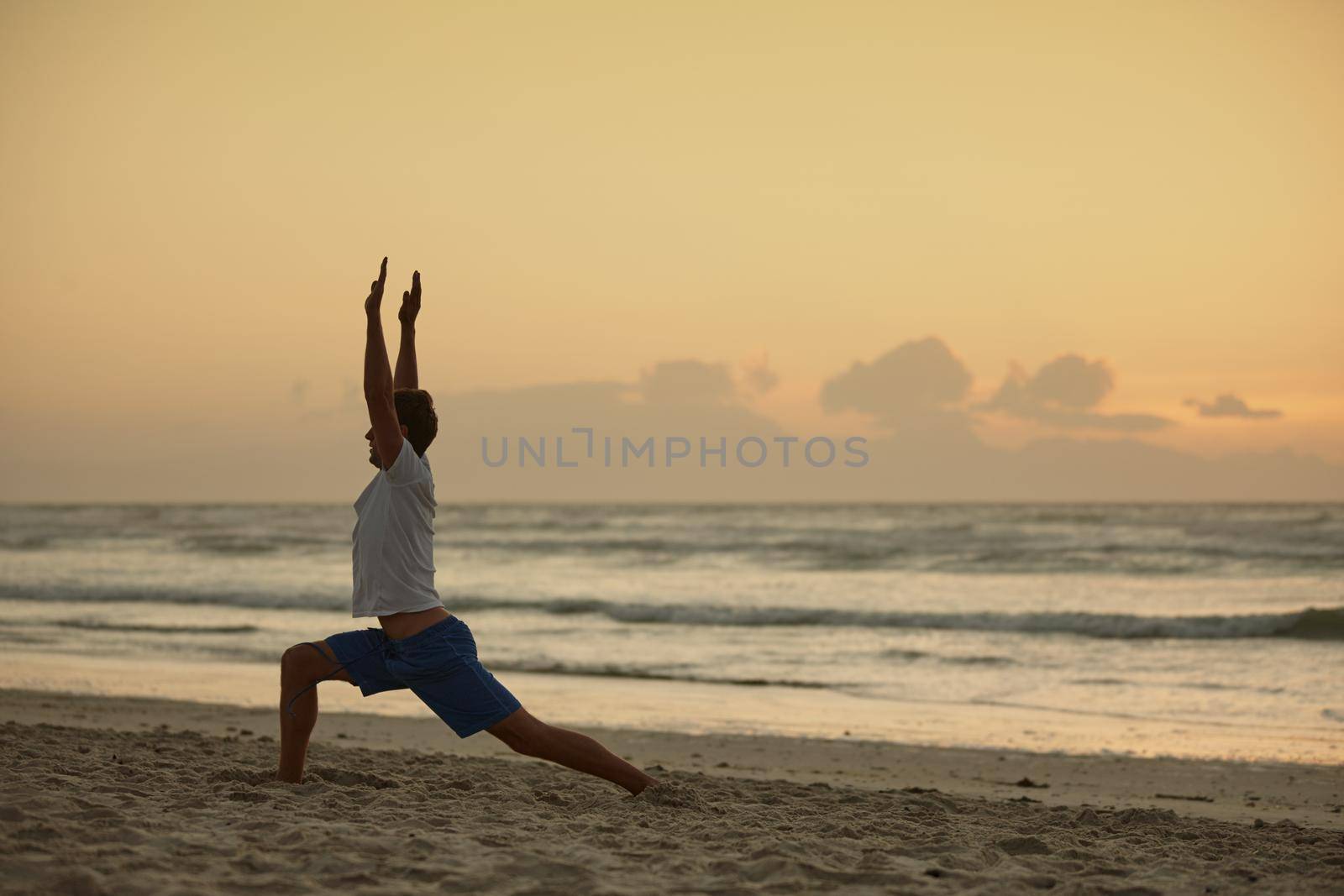 Yoga - the poetry of movement. a man doing yoga on the beach at sunset. by YuriArcurs