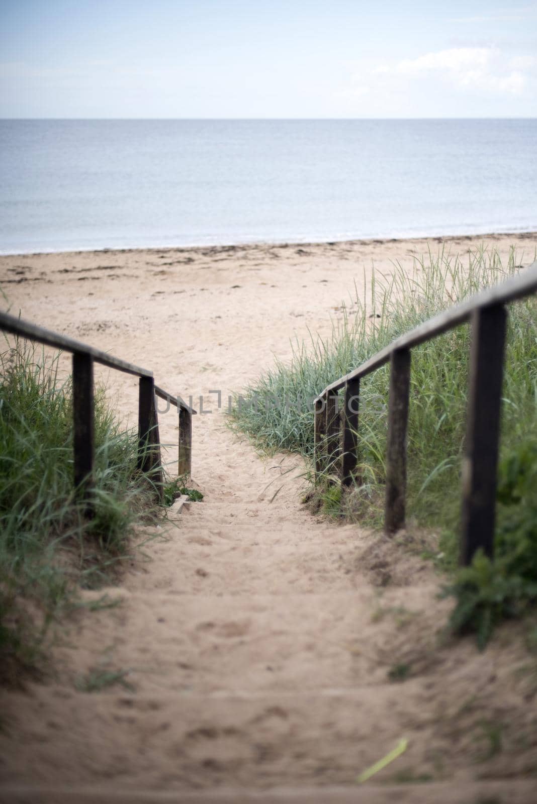 First person perspective view downward on sand covered stairs at spacious beach in Fife Coast, Scotland