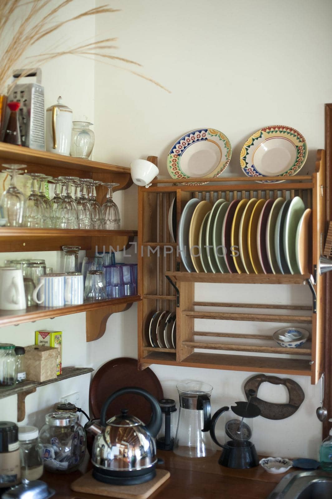 Country kitchen with glassware and crockery displayed on open wooden shelves and small appliances on a wooden counter