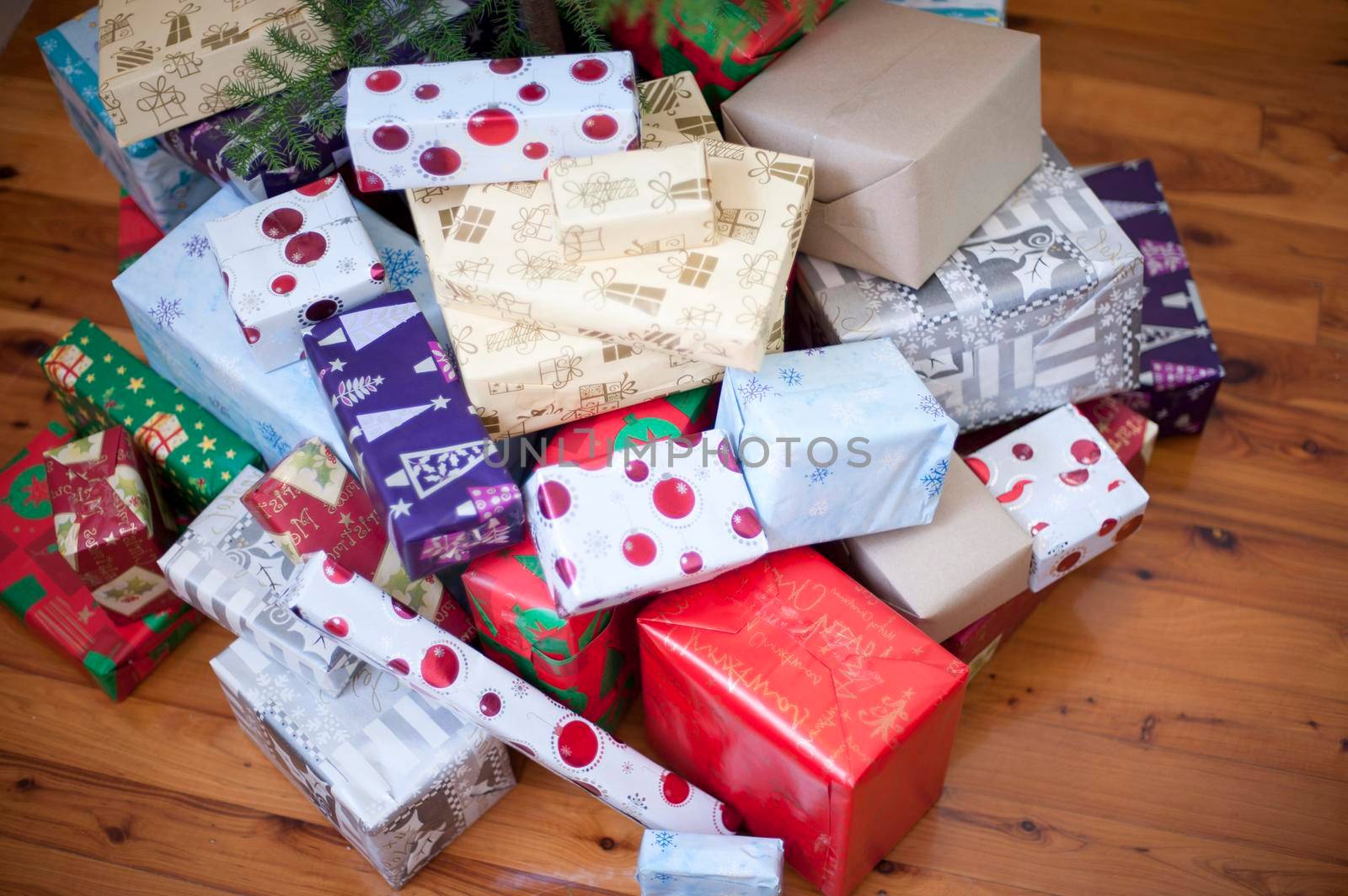 High angle view of a large pile of pretty colourful Christmas gifts in a variety of patterned gift wrap on a hardwood floor in a home