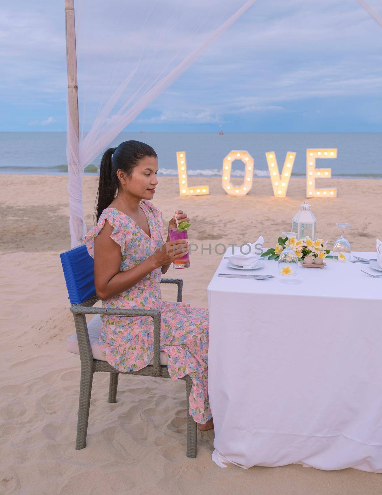 Romantic dinner on the beach of Huahin Thailand, dinner by candle light in Hua Hin , Valentine's concept. Asian women having dinner on the beach during sunset