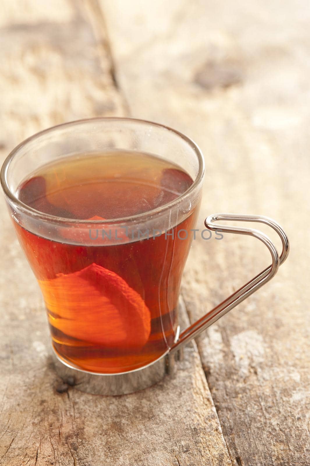 Freshly brewed hot black tea with lemon served in a glass mug for a refreshing drink, close up high angle on rustic wood