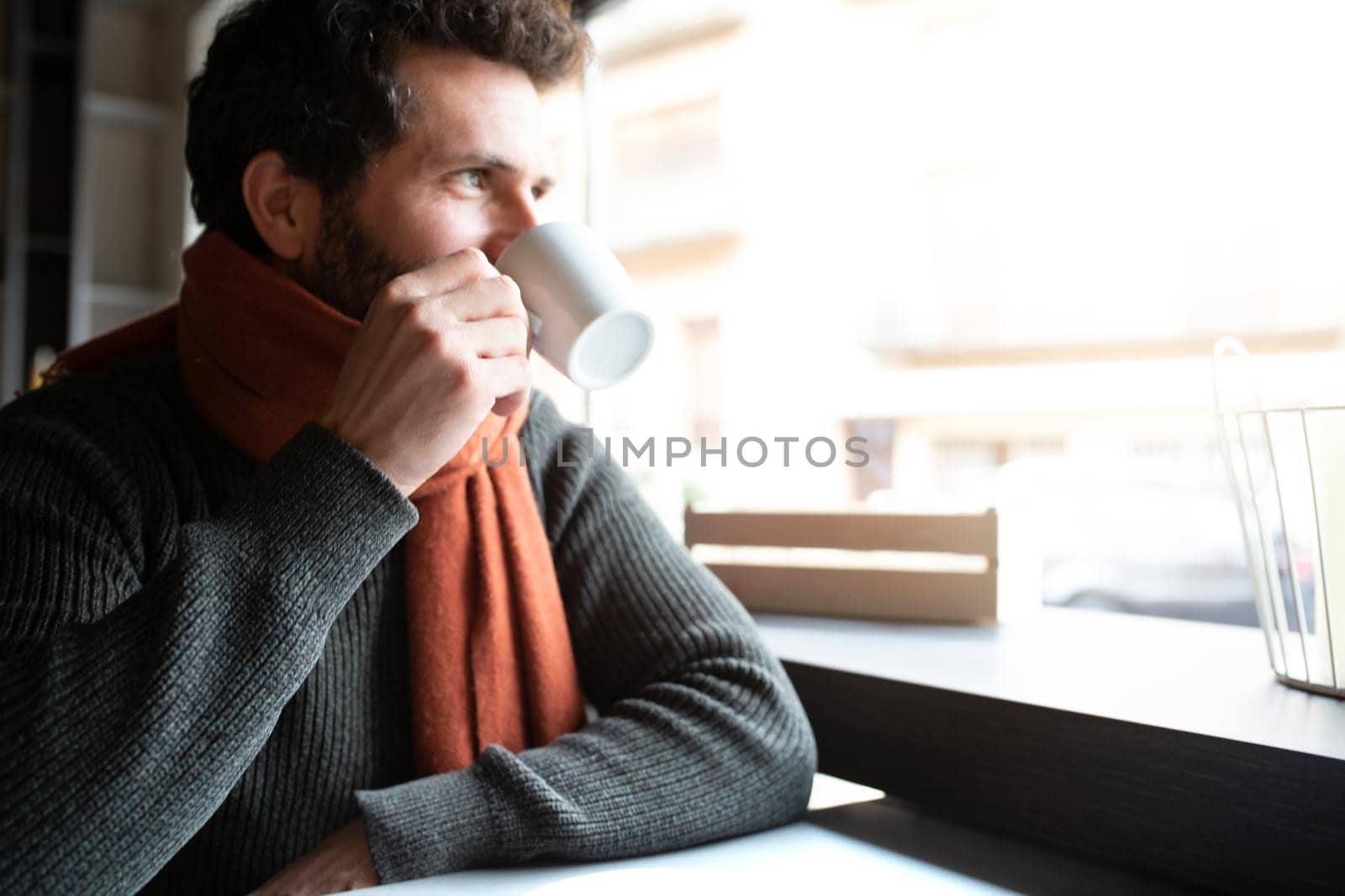 Pensive man looking out the window, drinking morning coffee in coffee shop. Copy space. Lifestyle.
