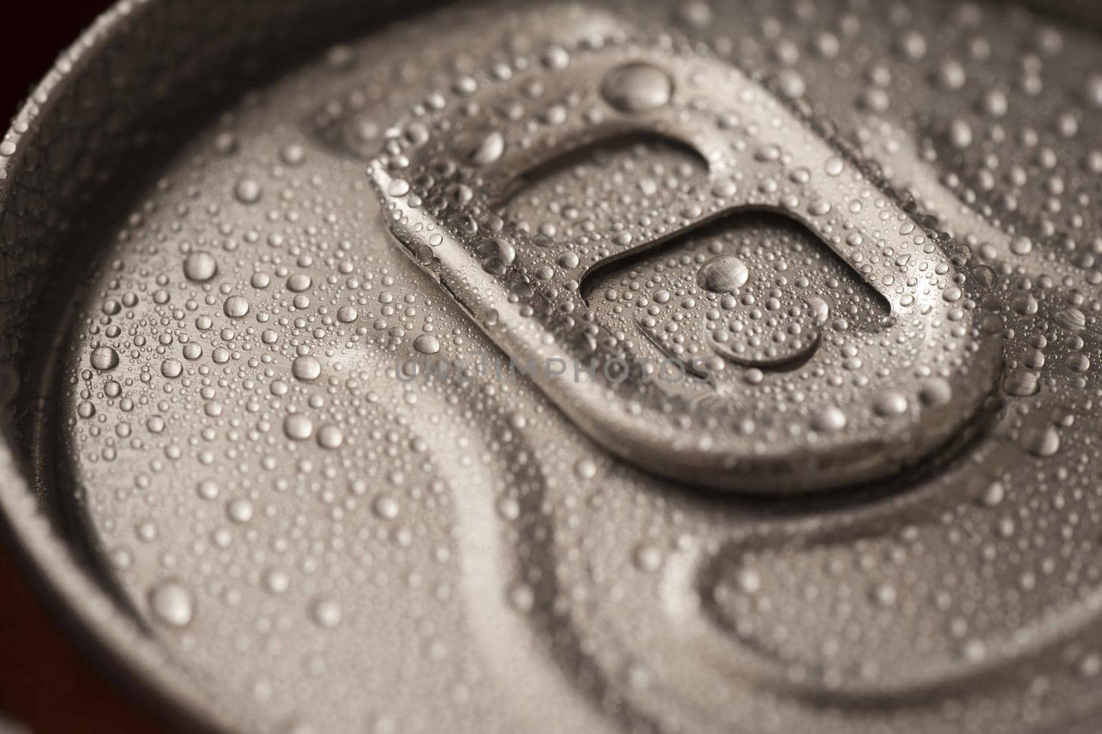 Ice cold beverage in a can with a closeup view of the unopened pull tab on the lid with condensed water droplets