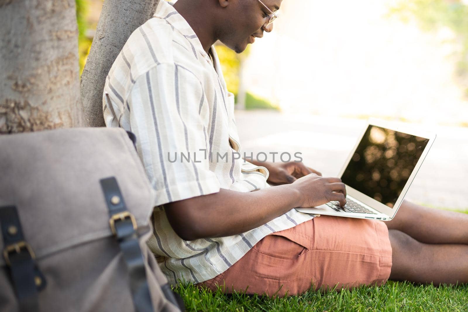 Black man using laptop outdoors. African american college student doing homework on campus. Copy space. Education and technology concepts.