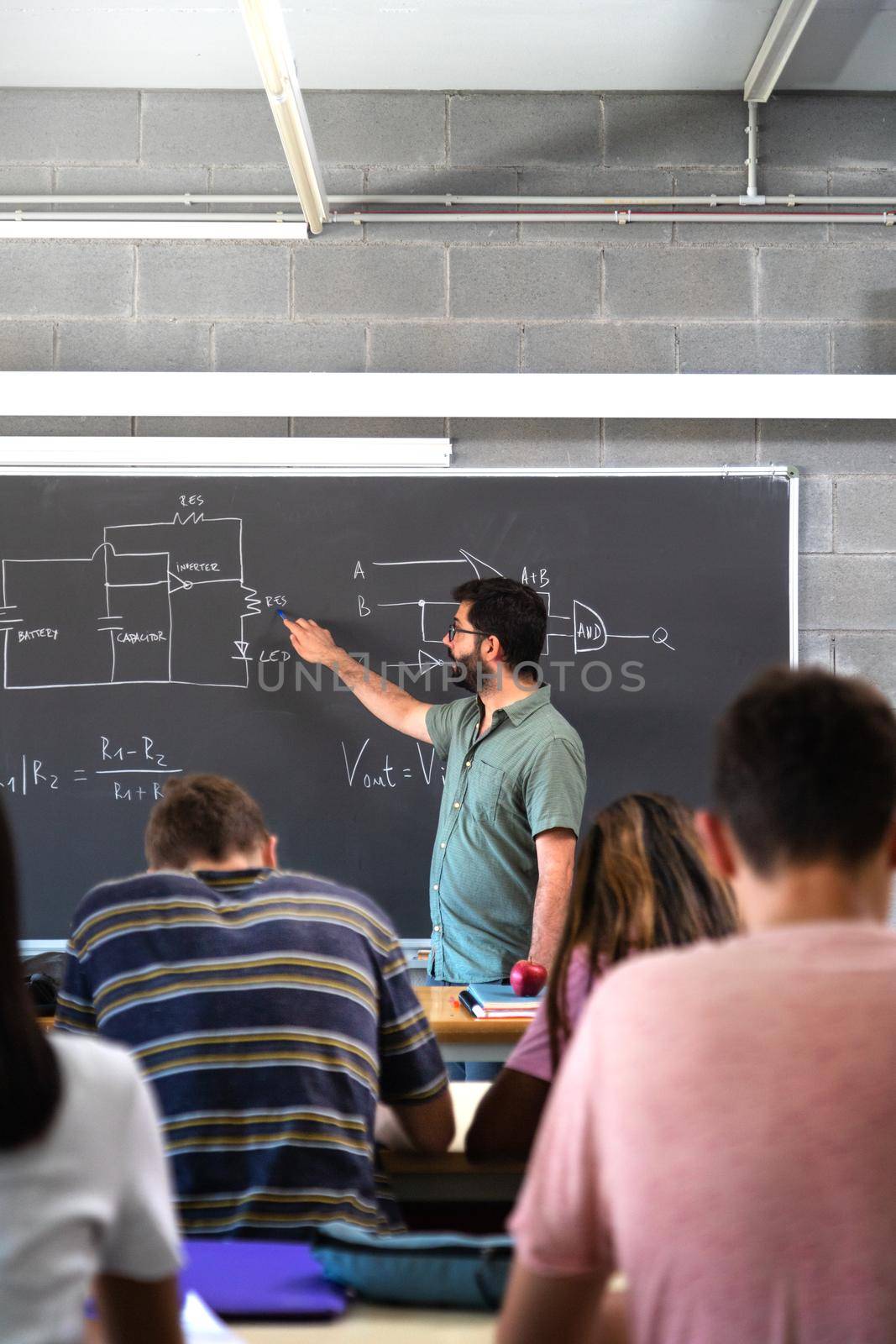 High school male teacher teaching lesson to multiracial teen students. Vertical image. Education concept.