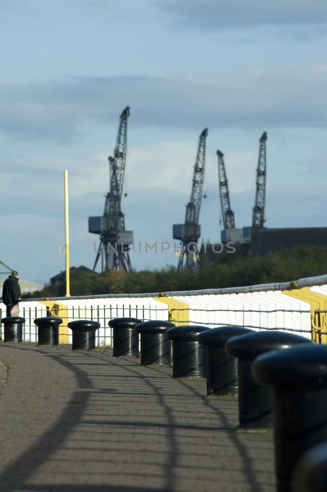 Various Large Cranes at the Shipyard Under a Stormy Sky Above.