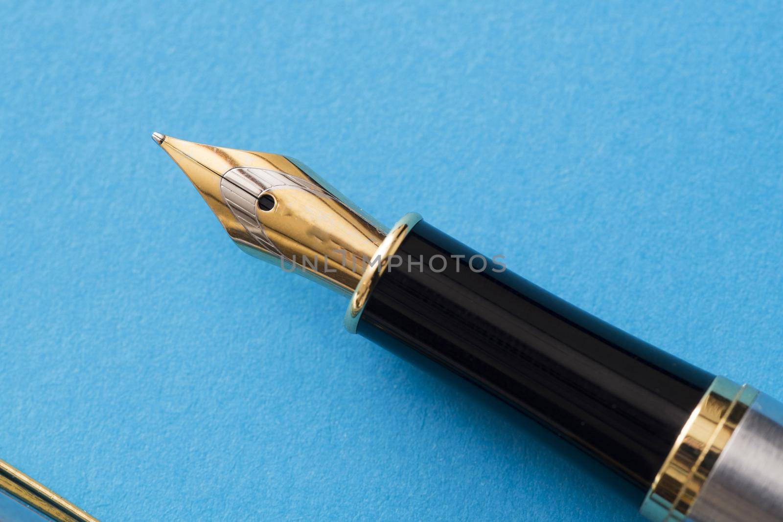 Close up of a calligraphy fountain pen tip isolated on a blue background with copy space.