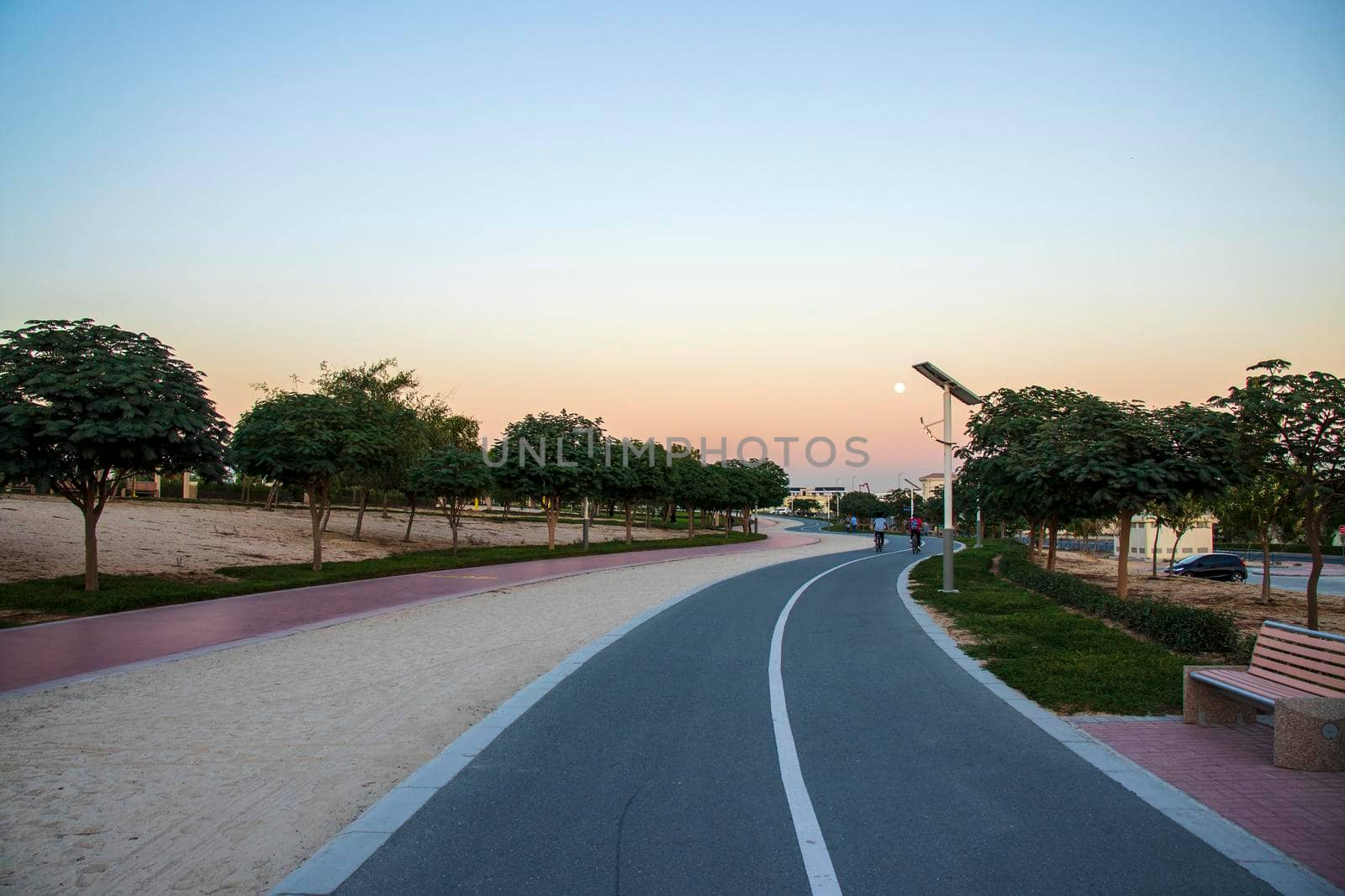 Jogging and cycling tracks in Al Warqa park, Dubai, UAE in the evening. Lamp post powered by solar panels can be seen in the picture.