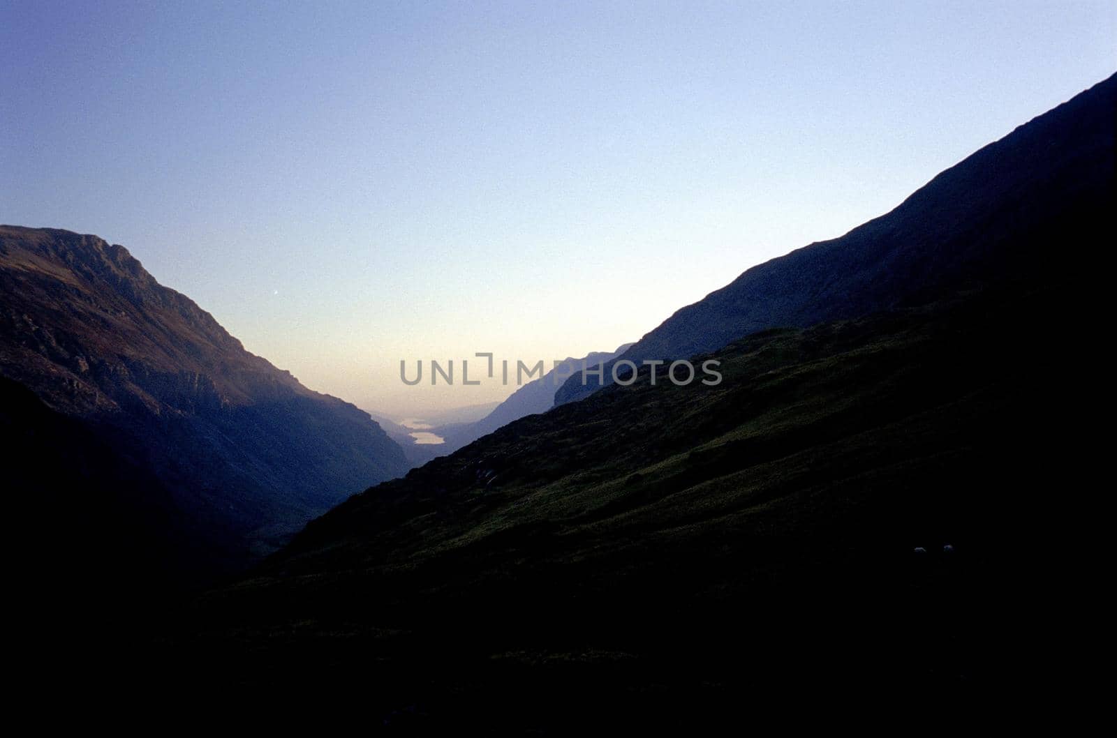 classic v shared valley with rocky hillsides and a lake in the distance