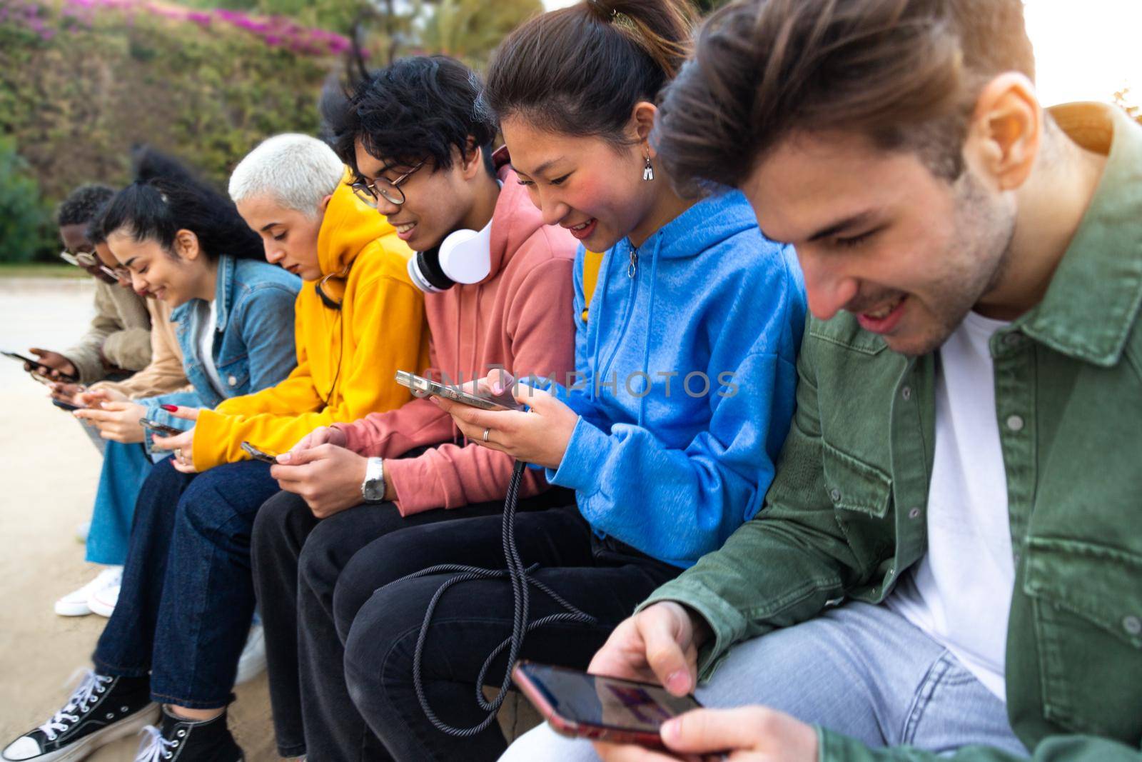 Group of diverse teenage college students ignoring each other using smartphone checking social media. by Hoverstock