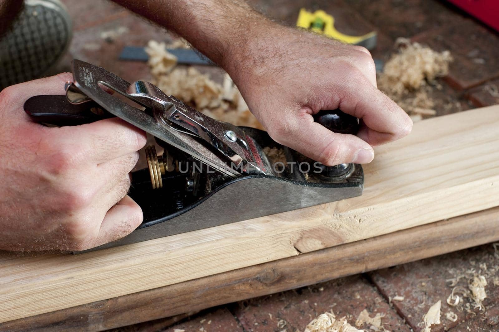 Man planing a plank of wood in a DIY concept by sanisra