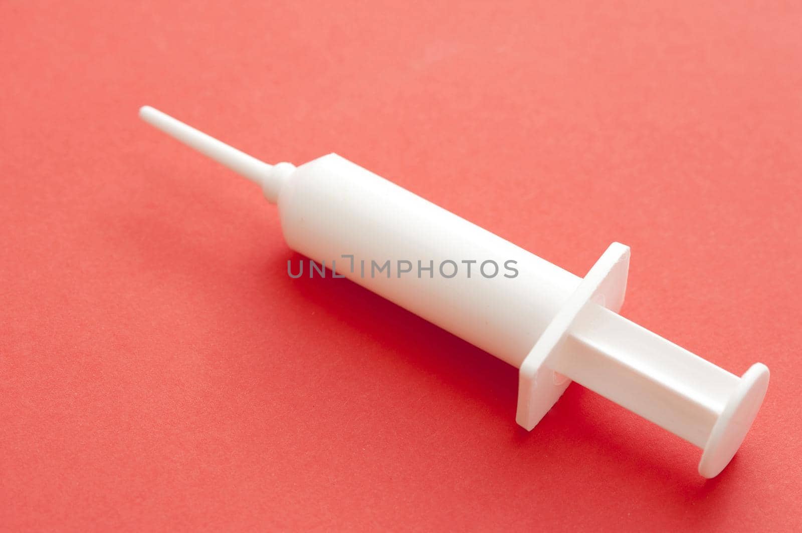 Vaccination Concept - Close up White Plastic Syringe on Pink Background, Isolated on Pink Background, Emphasizing Copy Space.