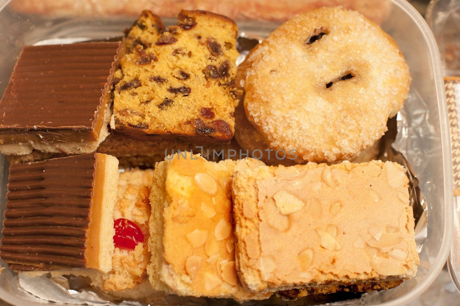 Assortment of small individual cakes displayed in a container on a buffet table at a catered event, overhead closeup view