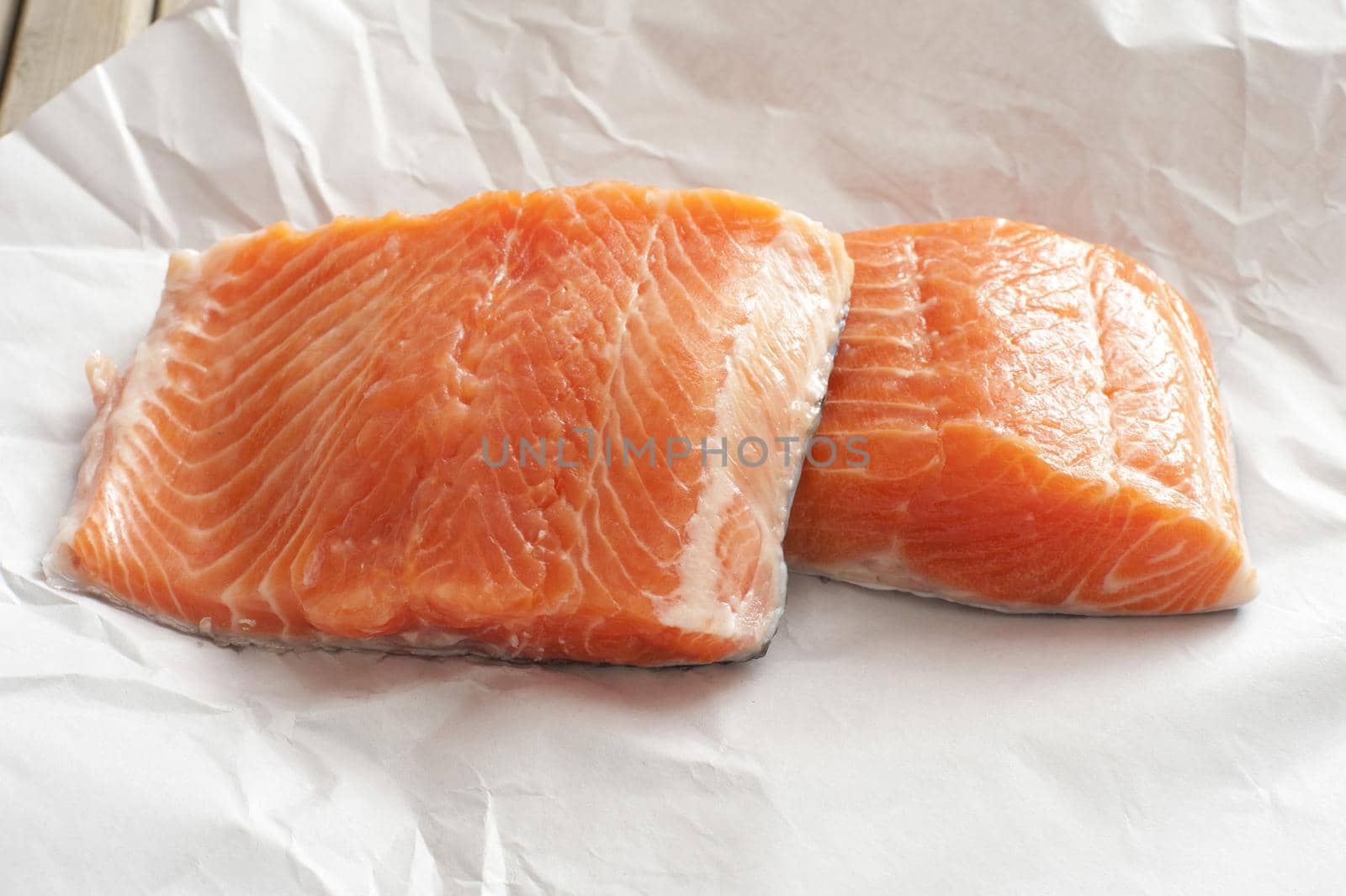 Pair of raw filleted salmon pieces on white butcher paper ready to be cooked or fried