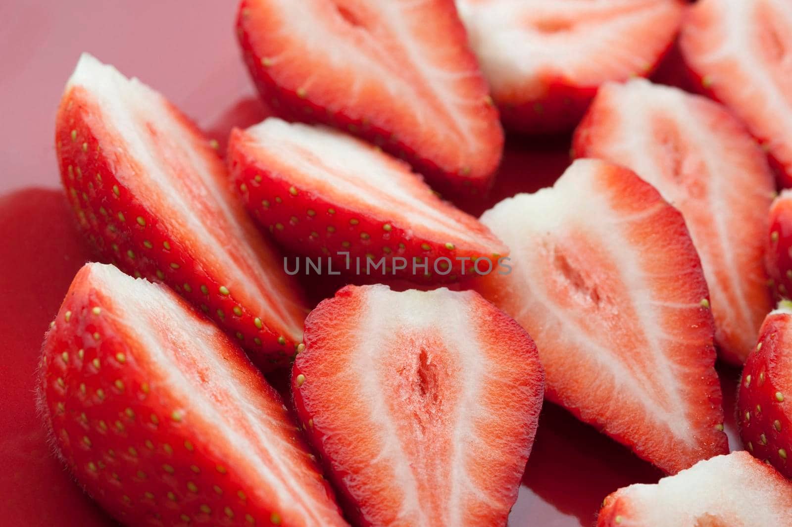 Close up view of halved strawberries showing the succulent sweet flesh during preparation of a delicious dessert