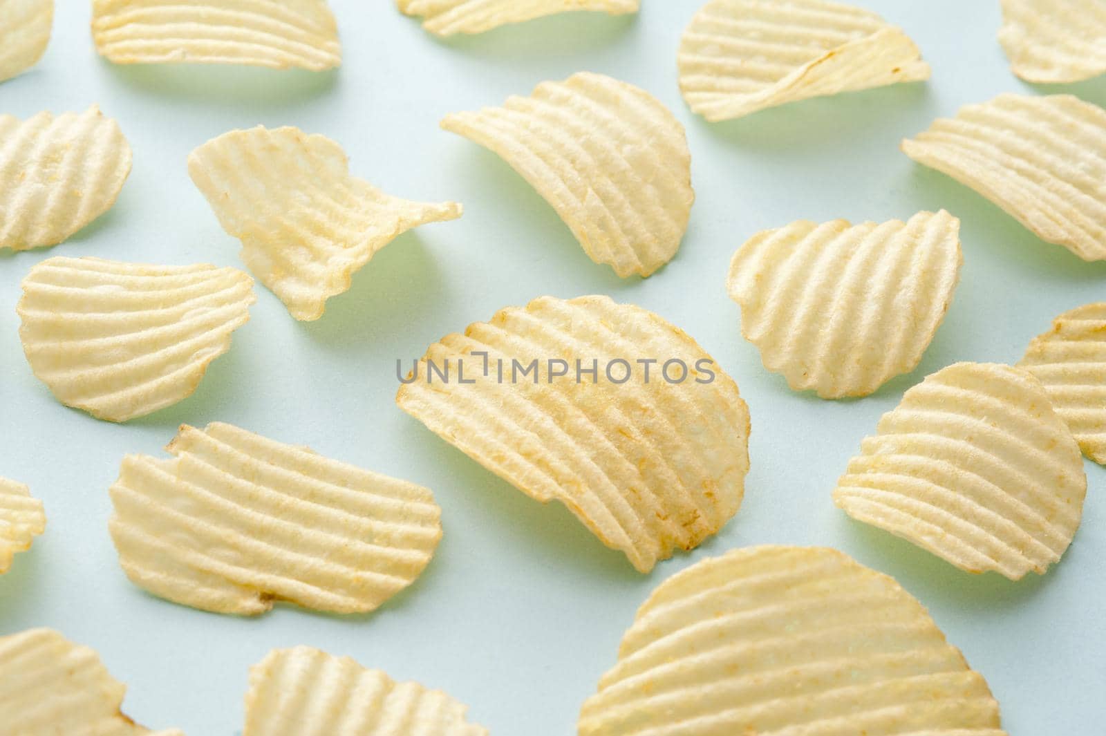 Group of separate full sized crispy ridged potato chips as background about snack food over blue