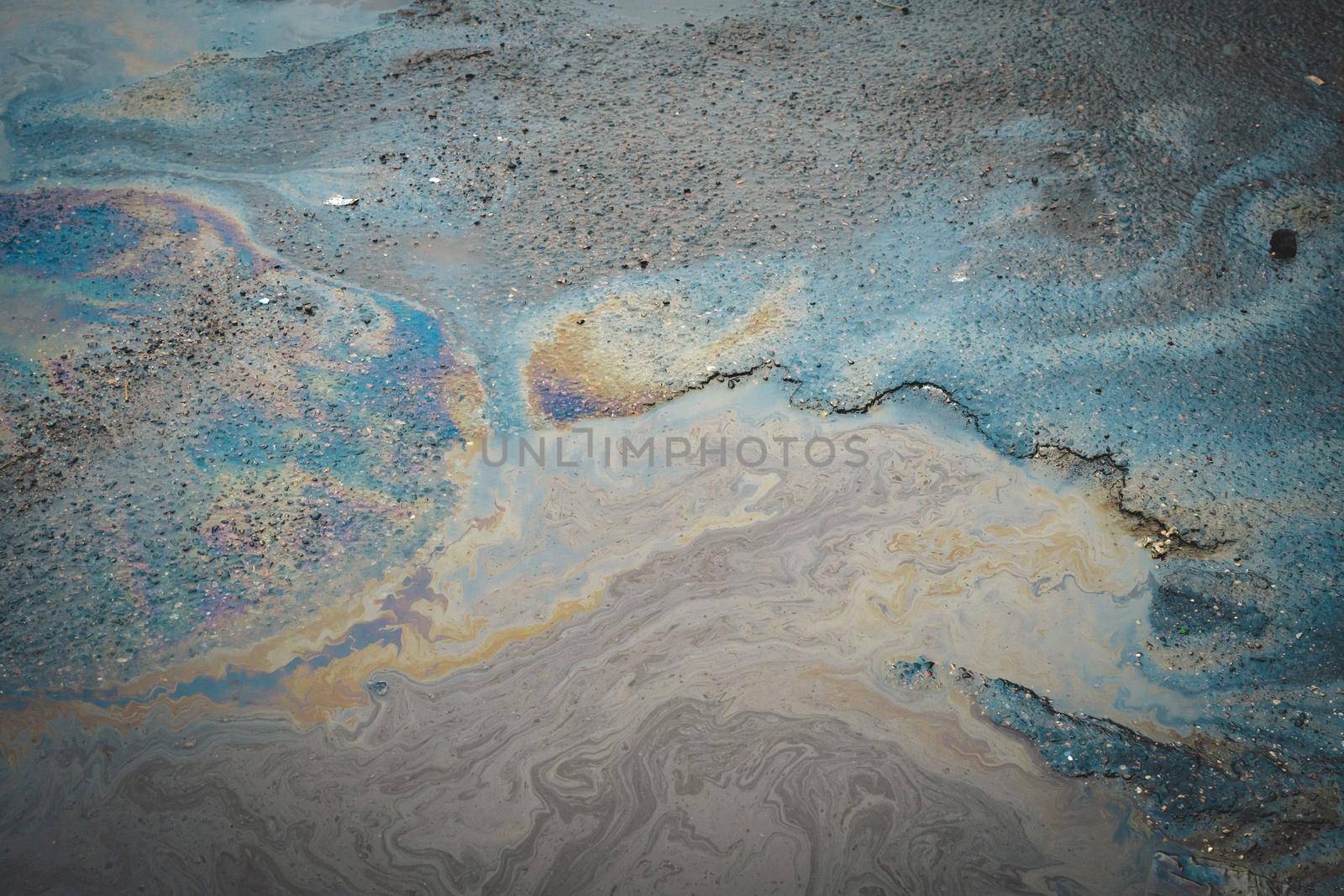 Multi-colored poisonous spots of spilled gasoline on wet asphalt. Environmental pollution concept