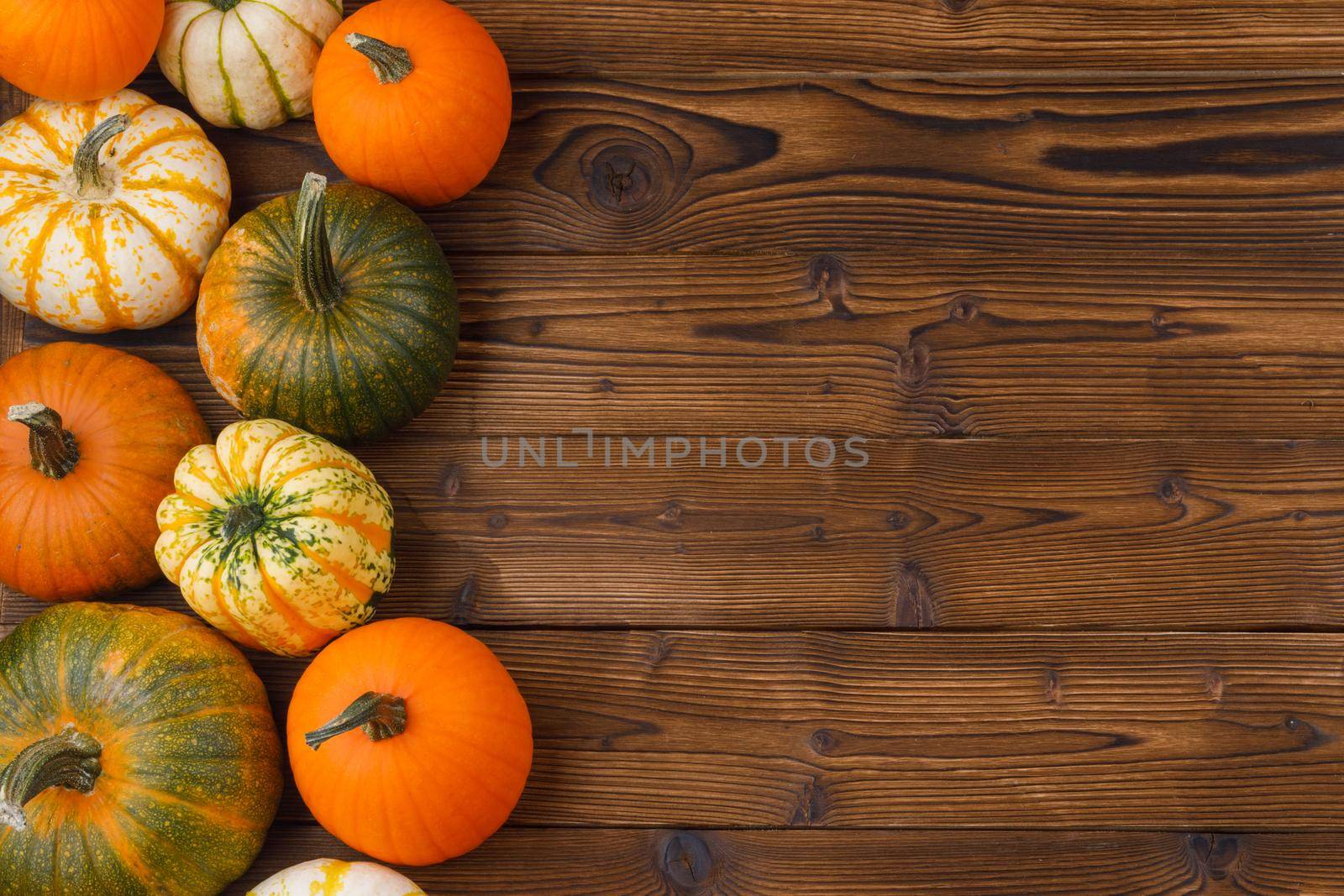 Different pumpkins on a wooden background, autumn theme, texture. Design ideas, top view. Halloween, Thanksgiving day