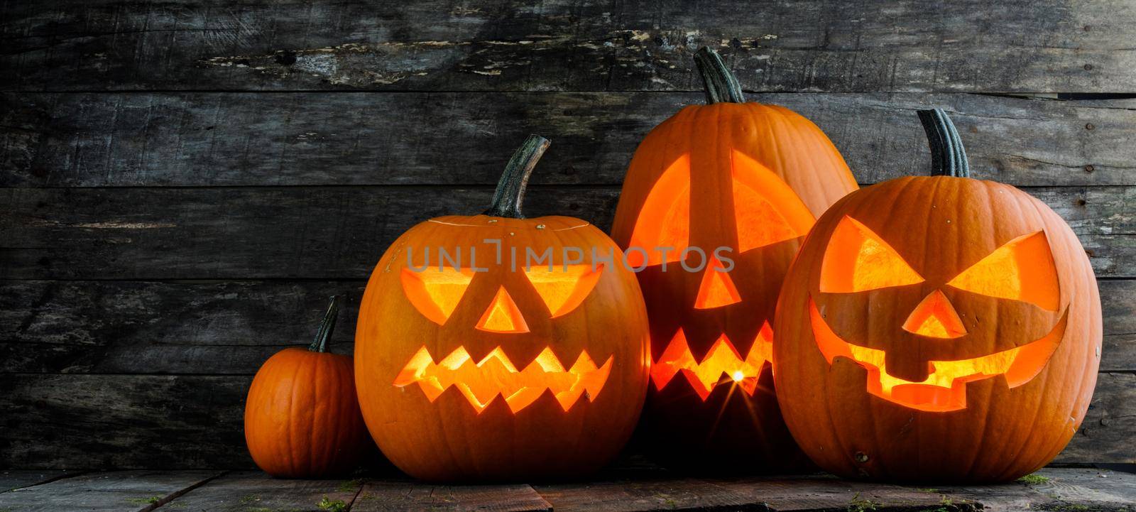 Group of Halloween pumpkins with candles inside on wooden background