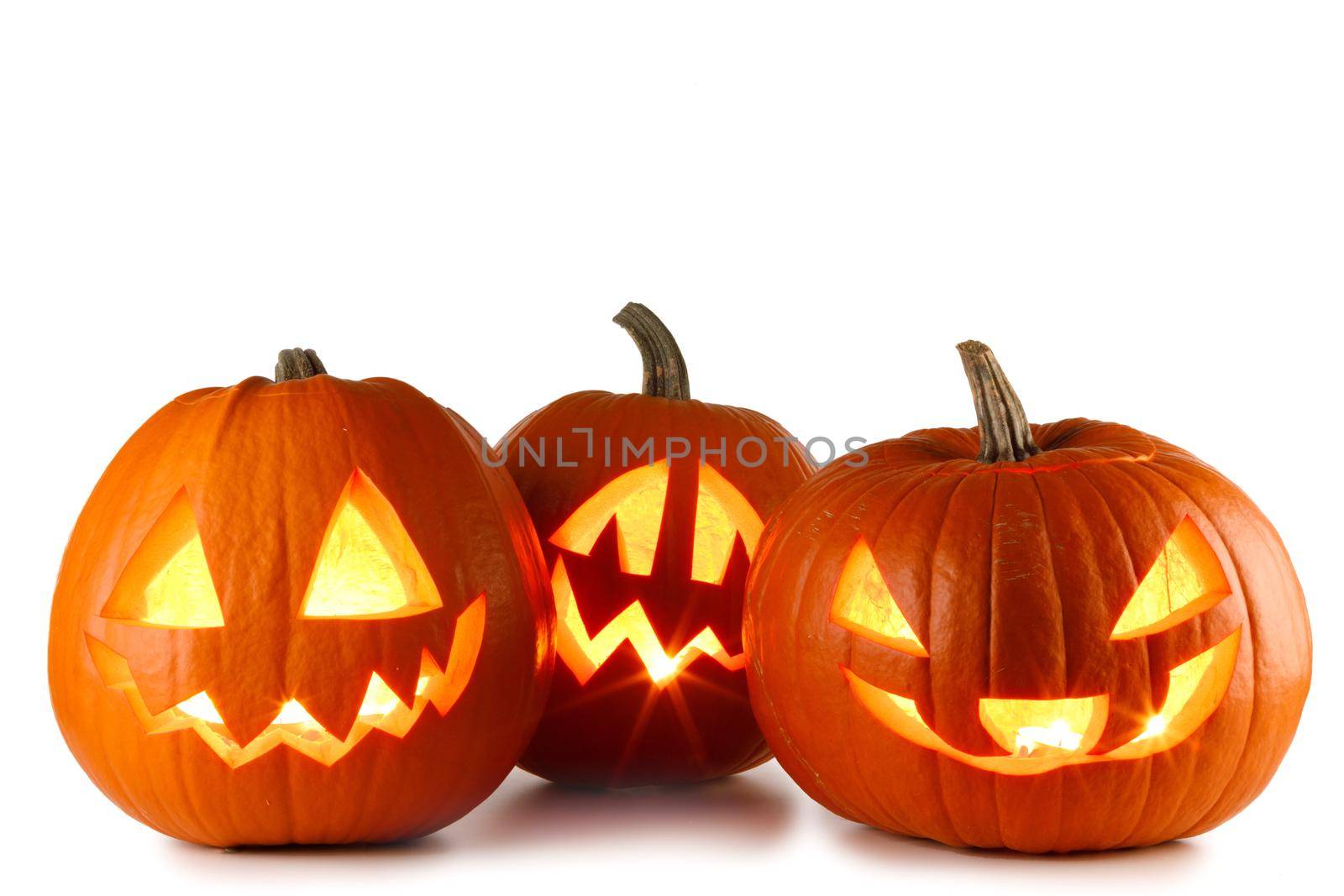 Three Halloween glowing lantern pumpkins in a row isolated on white background